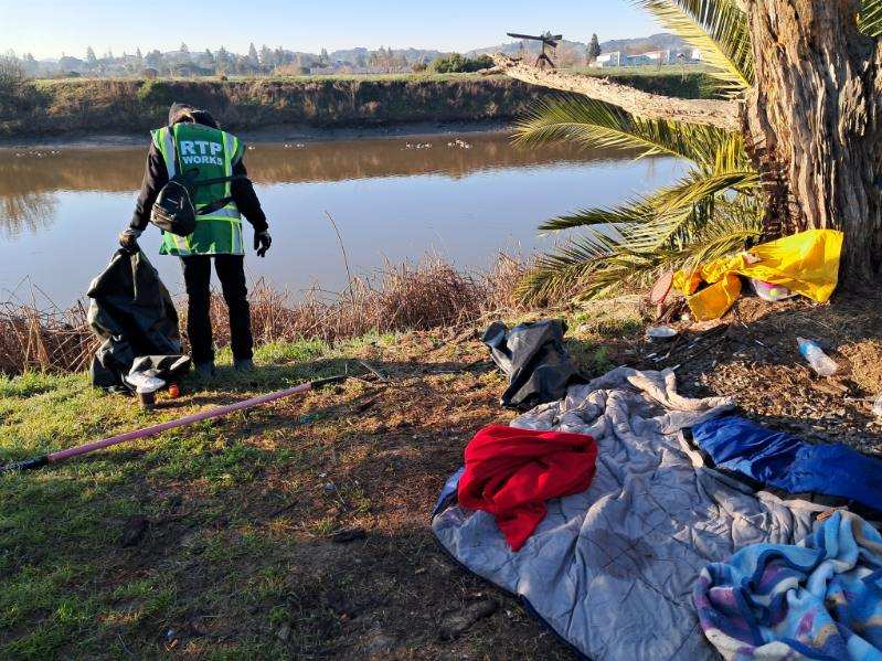 Man cleaning trash from around a river